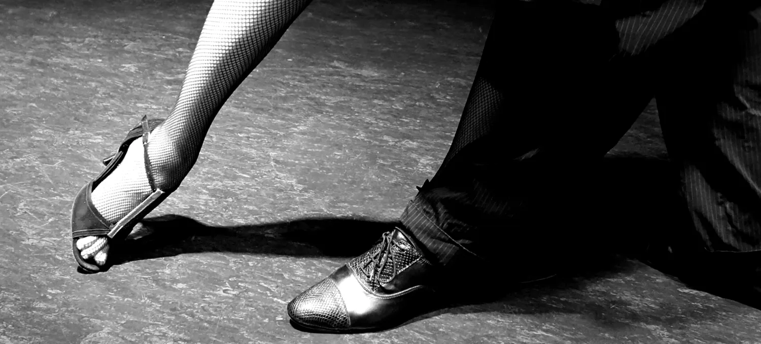 Pies de una pareja bailando tango en una clase para principiantes en Alicante